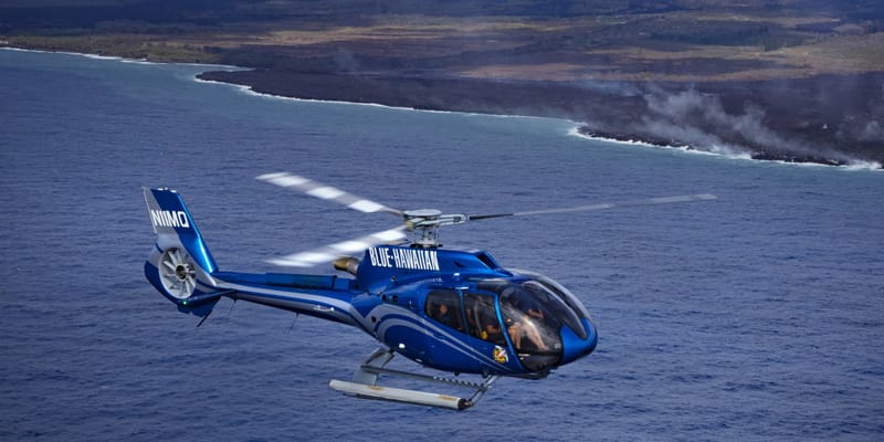 Helicopter flying along an active lava coastline